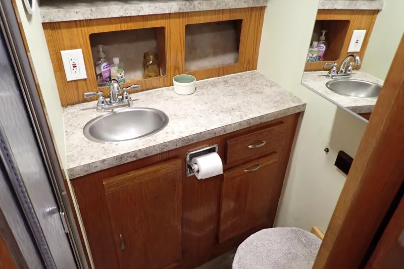 Slide: The Image of 1988 Mainship bathroom with sink, wooden cabinets, and toiletries on a marble countertop. - 20