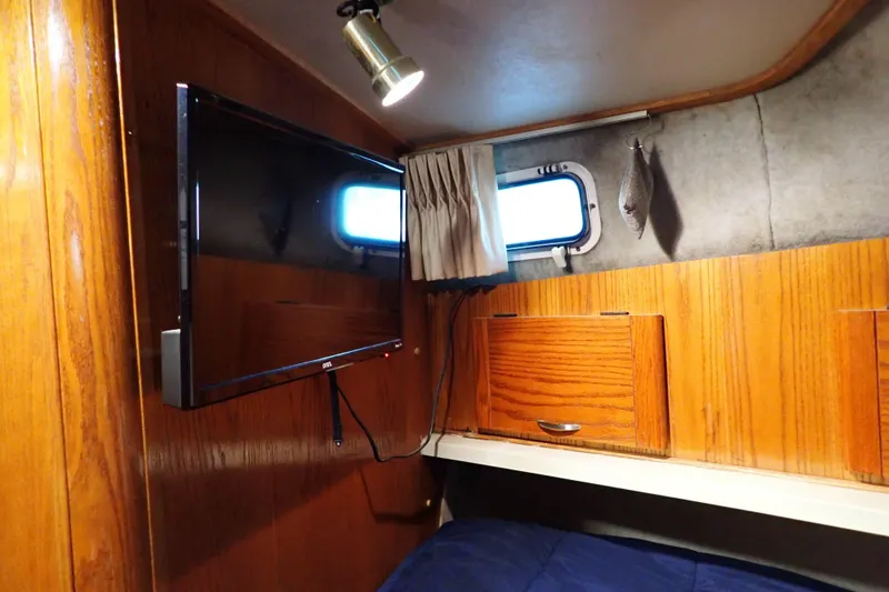 Slide: The Image of 1988 Mainship cabin interior with mounted TV, wooden cabinets, and small window. - 23