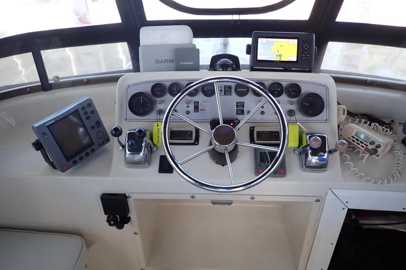 Slide: The Image of 1988 Mainship boat helm with steering wheel, navigation equipment, and control panels. - 24