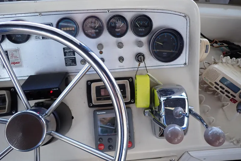 Slide: The Image of 1988 Mainship boat dashboard with steering wheel, gauges, and communication equipment. - 26