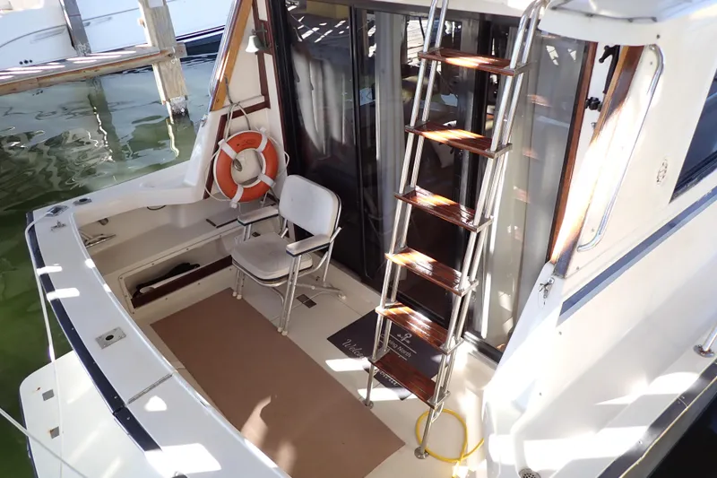 Slide: The Image of 1988 Mainship boat interior with ladder, chair, and life preserver in a marina setting. - 3