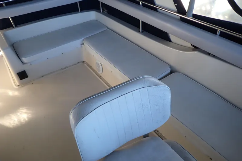 Slide: The Image of 1988 Mainship boat interior with white cushioned seating and chair. - 31