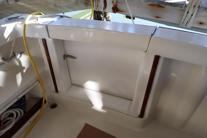Slide: The Image of 1988 Mainship boat interior with storage compartment and yellow hose. - 34