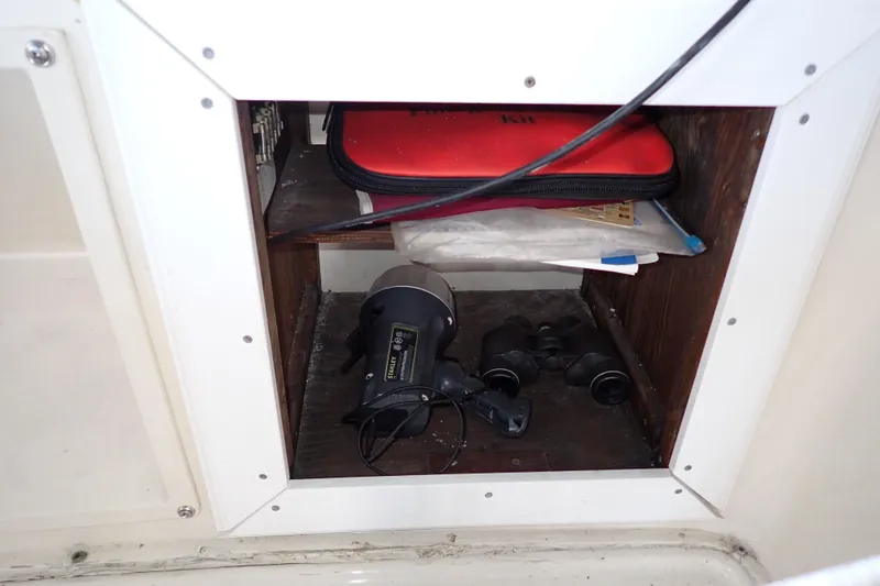 Slide: The Image of 1988 Mainship storage compartment with flashlight, binoculars, and red kit. - 38