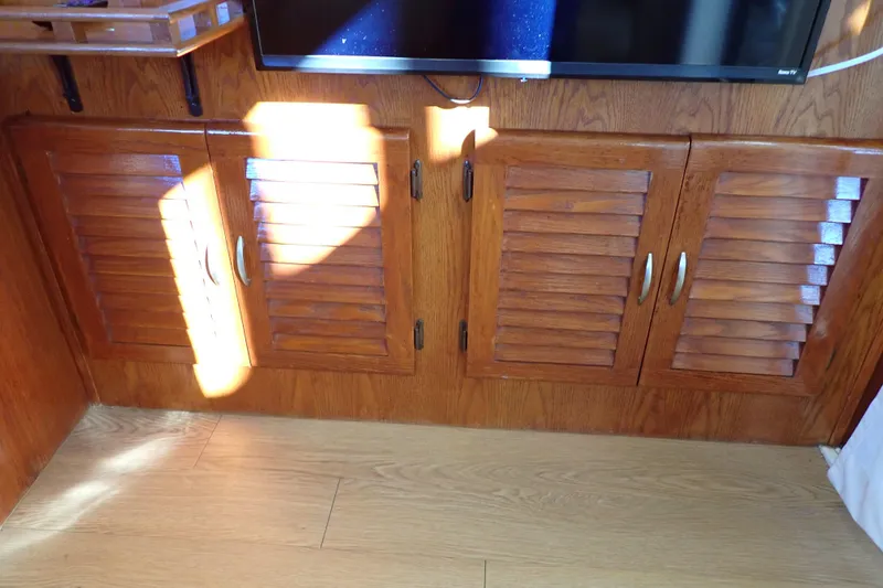 Slide: The Image of 1988 Mainship interior with wooden louvered cabinets and mounted TV. - 47