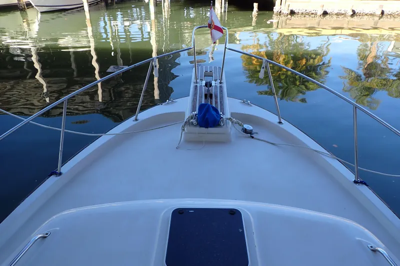 Slide: The Image of 1988 Mainship boat bow view in marina, calm water reflections, flag displayed. - 5