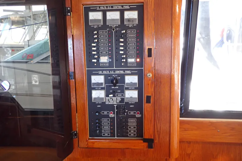 Slide: The Image of 1988 Mainship boat control panel with wooden frame, featuring 12V DC and 120V AC systems. - 51