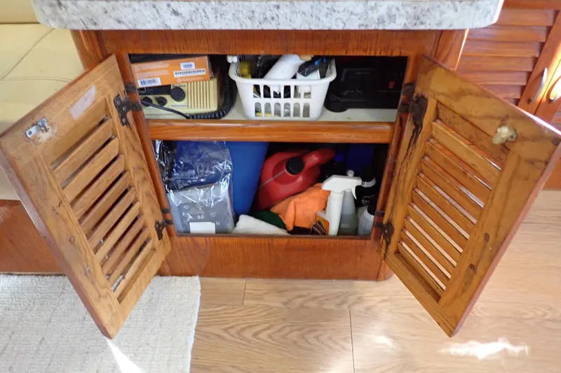 Slide: The Image of Open wooden cabinet on 1988 Mainship boat, storing cleaning supplies and tools. - 56