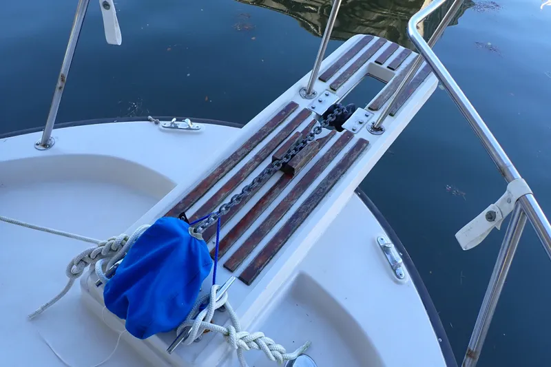 Slide: The Image of 1988 Mainship boat deck with anchor chain and blue bag on calm water. - 6