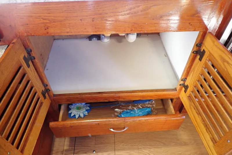 Slide: The Image of 1988 Mainship wooden cabinet with open doors and drawer, showcasing interior storage space. - 60