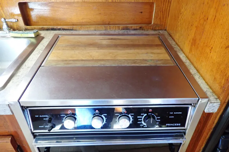 Slide: The Image of 1988 Mainship kitchen stove with wooden cover and stainless steel controls. - 65