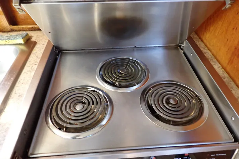 Slide: The Image of 1988 Mainship stove with three electric burners, stainless steel finish, and closed lid. - 66