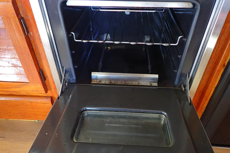 Slide: The Image of Open oven door on a 1988 Mainship boat, showcasing interior racks and wooden cabinetry. - 68