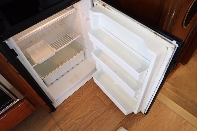 Slide: The Image of Open refrigerator in a 1988 Mainship boat, showing empty shelves and door compartments. - 71