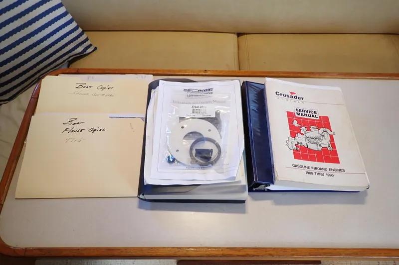 Slide: The Image of 1988 Mainship boat documents and Crusader service manual on a table. - 74