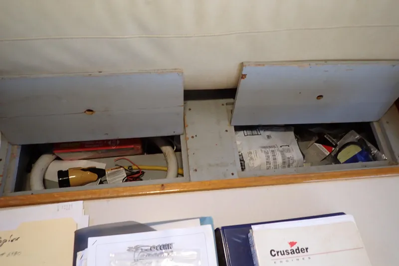Slide: The Image of 1988 Mainship storage compartments with various items and documents, including Crusader engine manual. - 76