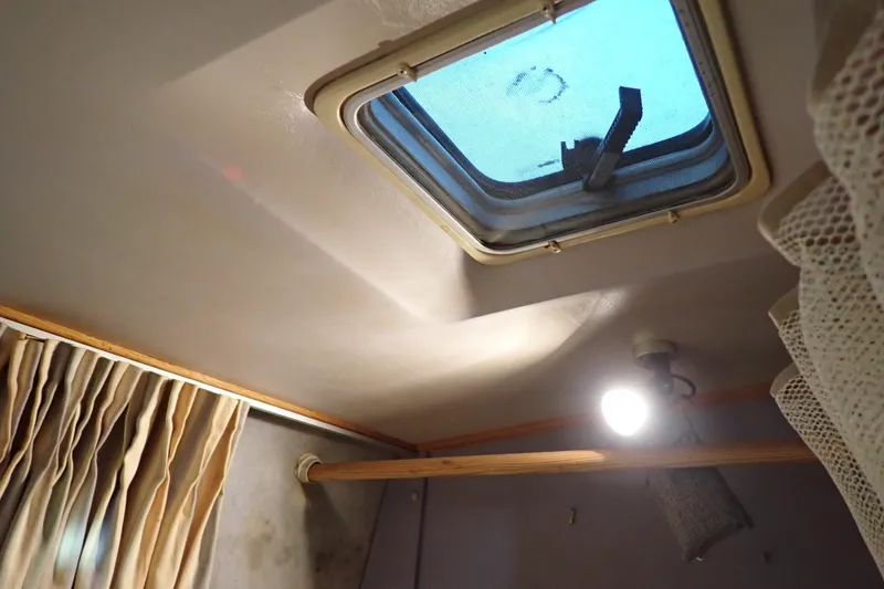 Slide: The Image of 1988 Mainship interior with skylight, curtains, and ceiling light. - 79