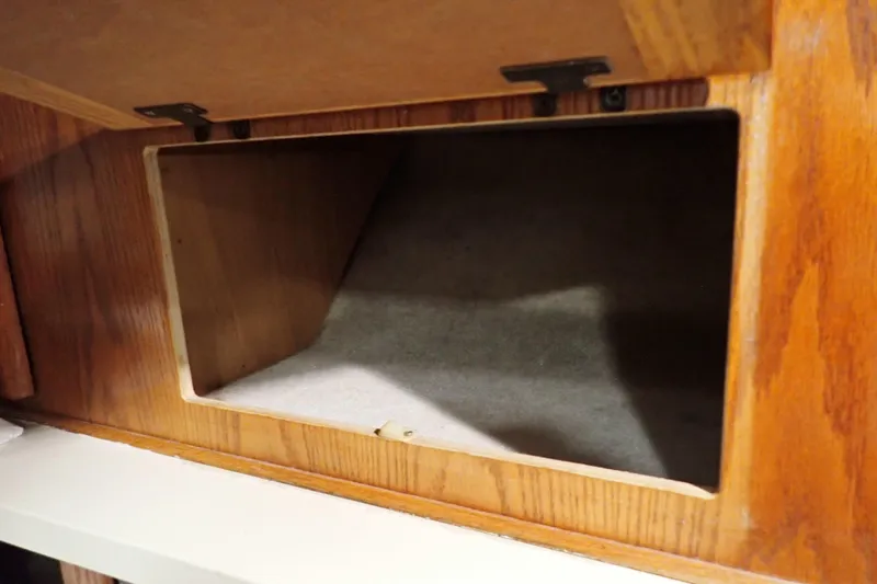 Slide: The Image of 1988 Mainship wooden storage compartment with open lid, showcasing interior space. - 83