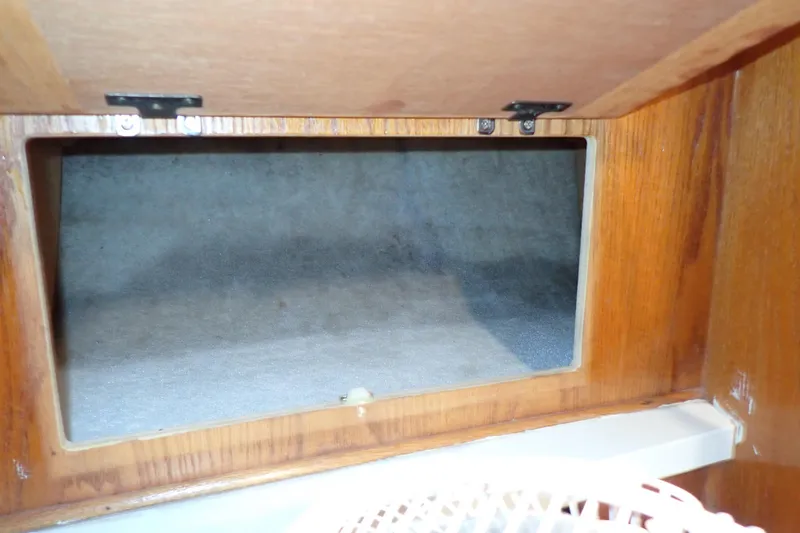 Slide: The Image of 1988 Mainship boat interior storage compartment with wooden frame and open door. - 84