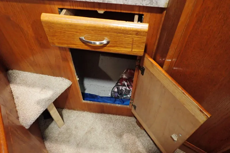 Slide: The Image of Open cabinet and drawer in 1988 Mainship boat interior, featuring wooden finish and carpeted floor. - 88