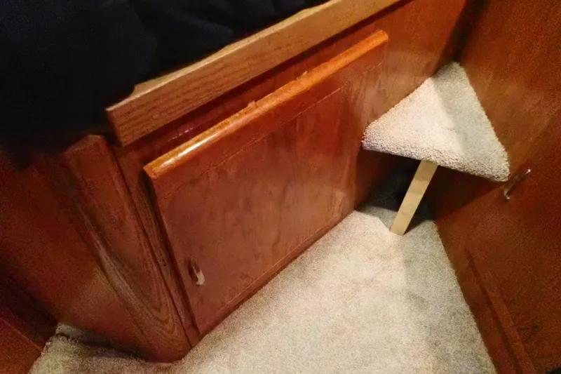 Slide: The Image of 1988 Mainship interior with wooden cabinetry and carpeted step detail. - 89