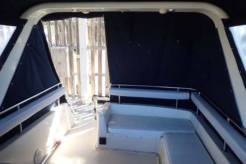 Slide: The Image of 1988 Mainship boat interior with cushioned seating and dark curtains. - 9