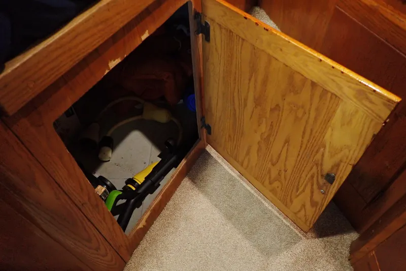 Slide: The Image of Open wooden cabinet on 1988 Mainship boat, revealing storage space with various items. - 90