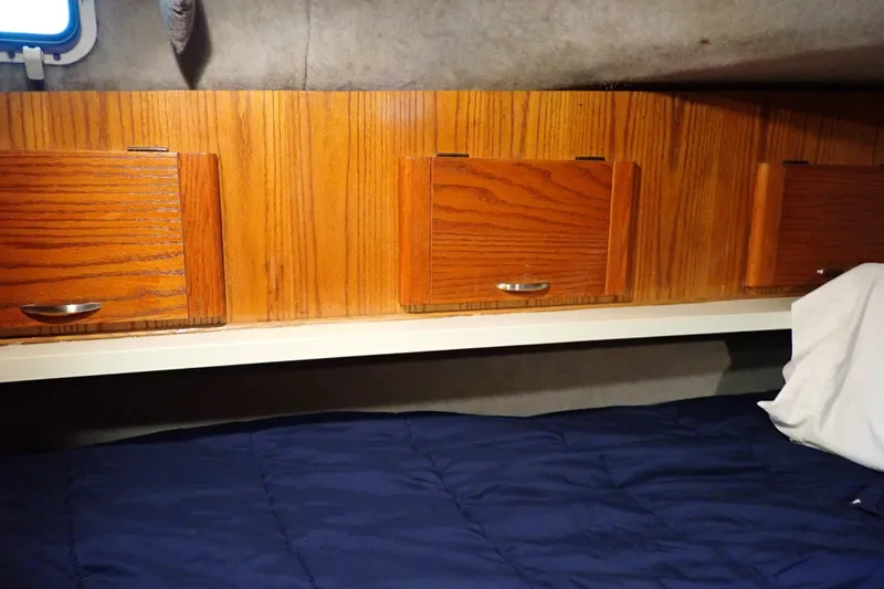 Slide: The Image of 1988 Mainship cabin interior with wooden cabinets and blue bedding. - 91