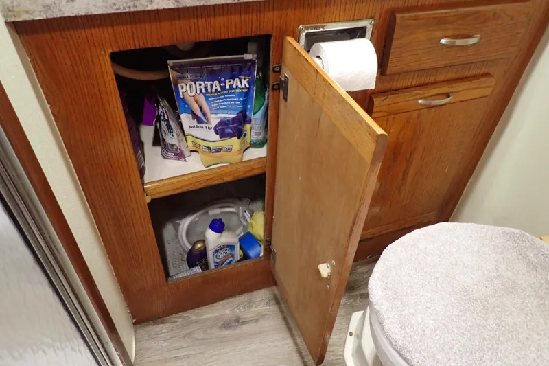 Slide: The Image of 1988 Mainship bathroom cabinet with cleaning supplies and toilet paper. - 94