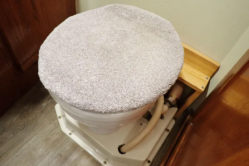 Slide: The Image of 1988 Mainship marine toilet with plush cover in a wooden interior setting. - 96