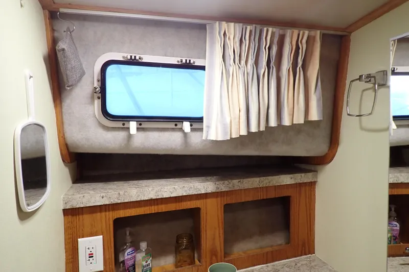 Slide: The Image of 1988 Mainship boat interior with window, curtains, and countertop storage. - 97