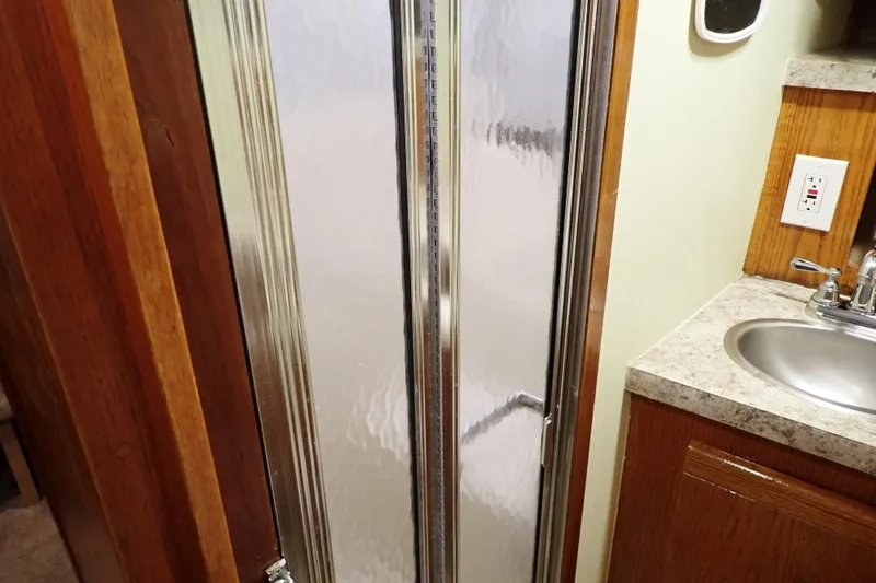 Slide: The Image of 1988 Mainship bathroom with shower, sink, and wooden cabinetry. - 98