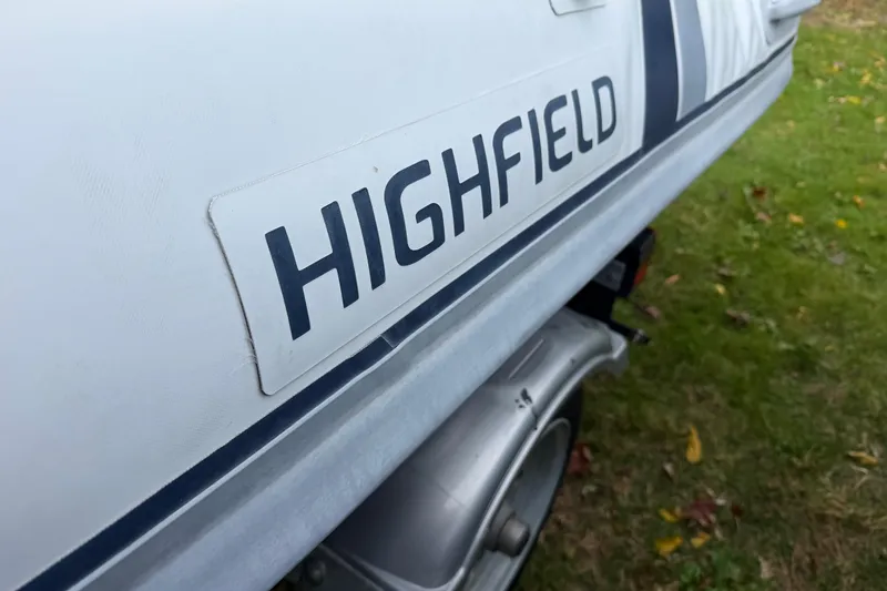 Slide: The Image of 2019 Highfield Classic 380 boat, close-up of logo on hull, parked on grass. - 9