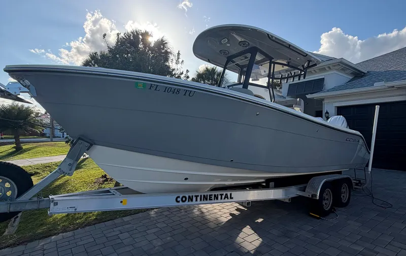 Slide: The Image of 2024 Cobia 240 Center Console boat on trailer in front of house. - 2