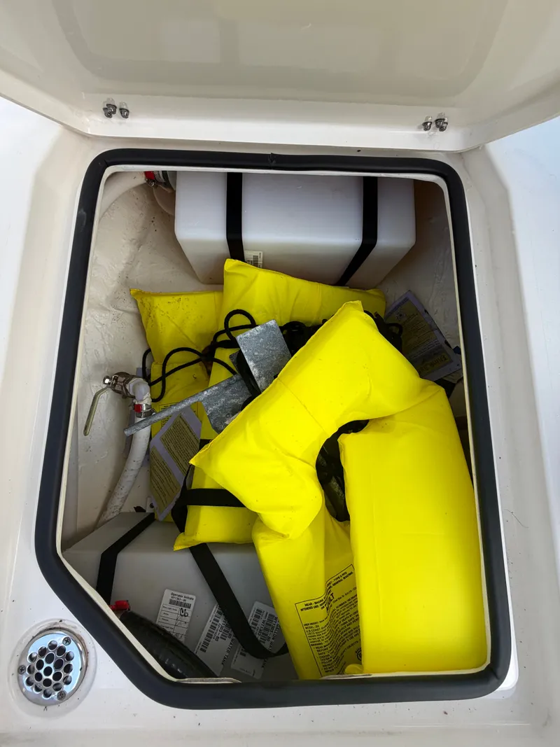 Slide: The Image of Storage compartment with life jackets on 2024 Cobia 240 Center Console. - 24