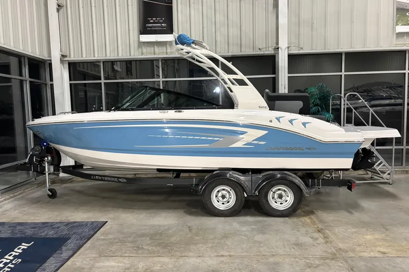 The Image of 2026 Chaparral 21 SSi boat in showroom, blue and white design on trailer. - 0
