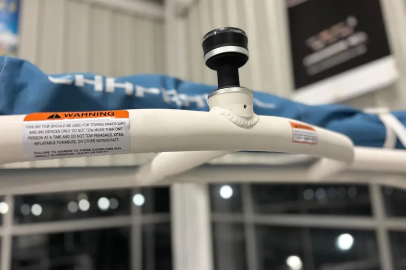 Slide: The Image of 2026 Chaparral 21 SSi ski tow bar with safety warning label in a showroom. - 23