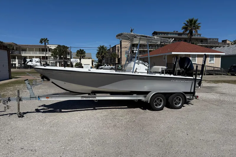 The Image of 2003 Kenner 21 V Tunnel boat on trailer, parked outdoors under clear blue sky. - 0