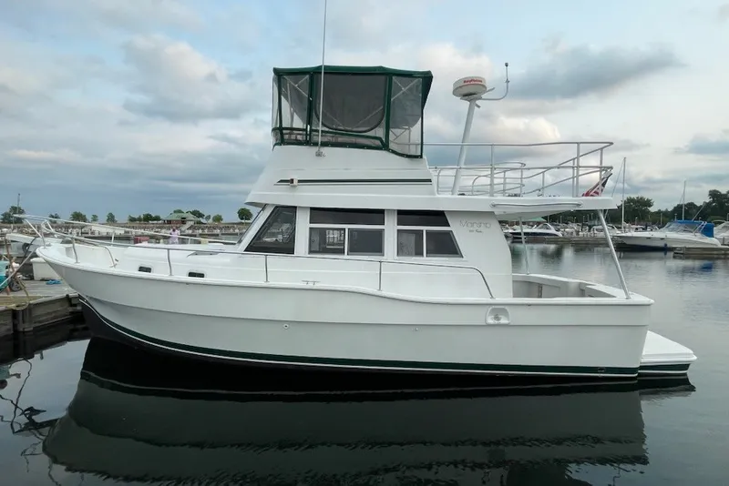 Slide: The Image of 1997 Mainship 350 Trawler docked at marina, featuring classic white design and spacious upper deck. - 23