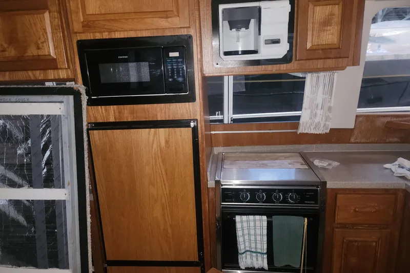 Slide: The Image of 1997 Mainship 350 Trawler kitchen with microwave, oven, and wooden cabinetry. - 13