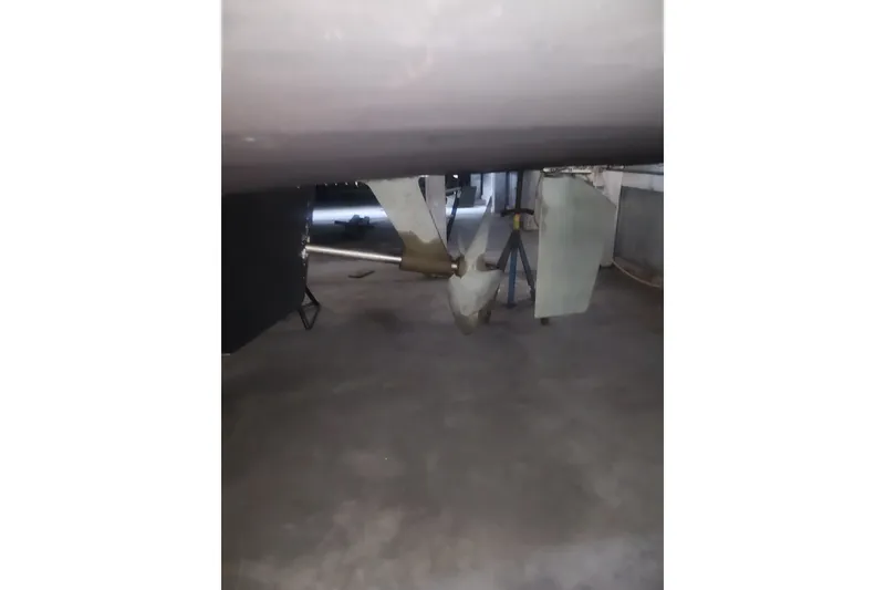 Slide: The Image of 1997 Mainship 350 Trawler propeller and rudder in a dry dock setting. - 16