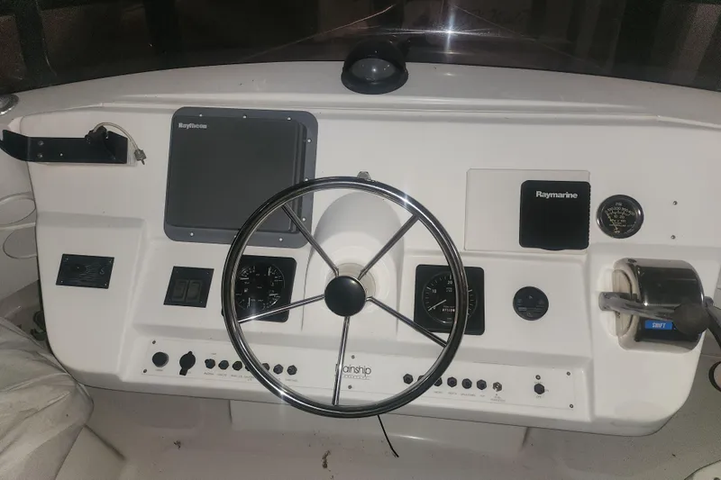 Slide: The Image of 1997 Mainship 350 Trawler helm with steering wheel, Raymarine electronics, and control panel. - 5
