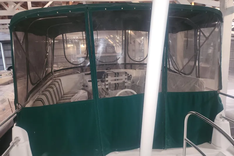 Slide: The Image of 1997 Mainship 350 Trawler with green canopy, docked indoors. - 6