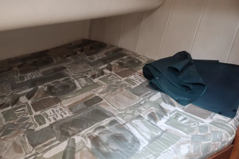 Slide: The Image of Interior cabin of 1997 Mainship 350 Trawler with patterned bedding and folded fabric. - 20
