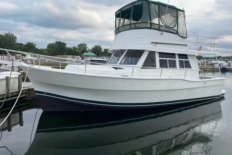 The Image of 1997 Mainship 350 Trawler docked at marina, featuring white hull and green canopy. - 0