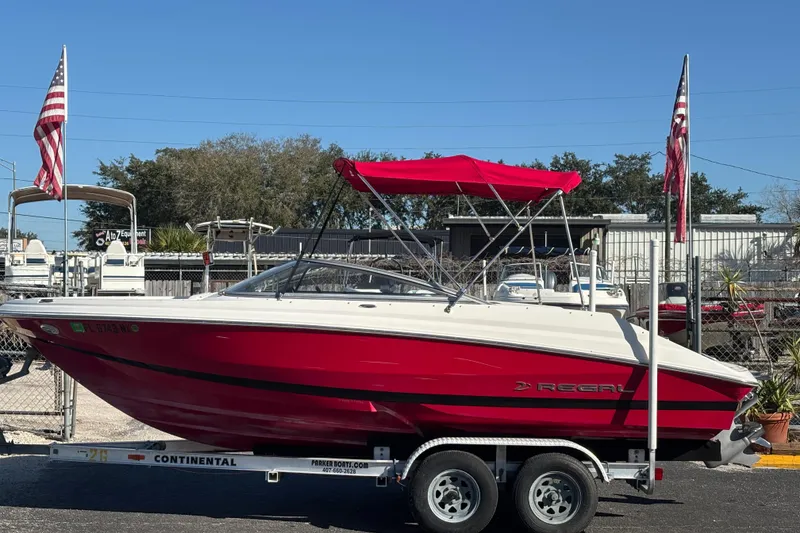 The Image of 2008 Regal 2000 Bowrider boat with red canopy on trailer, parked outdoors. - 0
