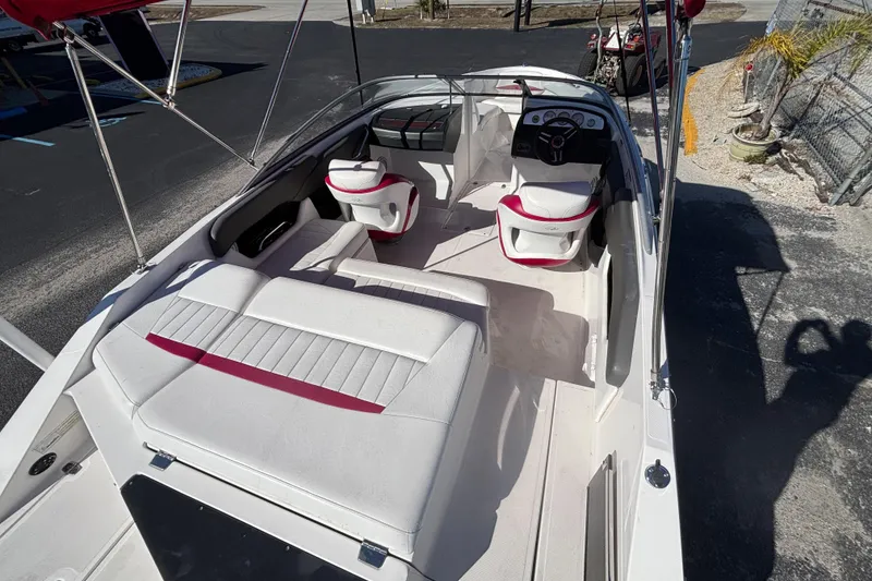 Slide: The Image of 2008 Regal 2000 Bowrider boat interior with white and red seating, parked outdoors. - 14