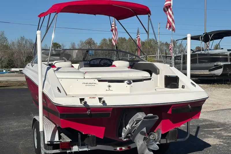 Slide: The Image of 2008 Regal 2000 Bowrider boat with red canopy and American flags in background. - 2