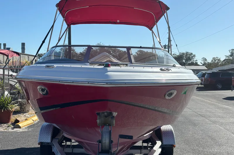 Slide: The Image of 2008 Regal 2000 Bowrider boat with red canopy on trailer, parked outdoors. - 7