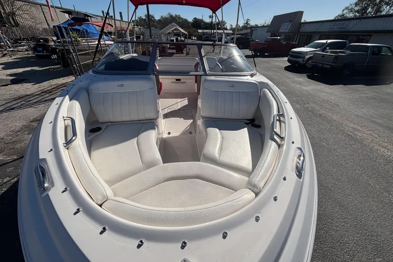 Slide: The Image of 2008 Regal 2000 Bowrider boat with white seating and red canopy in a parking lot. - 9